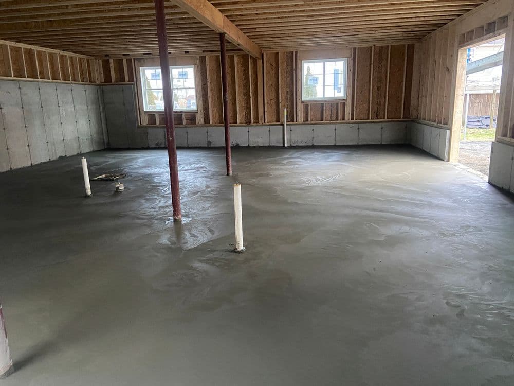 Freshly poured concrete floor in a new construction home’s basement with framed walls.
